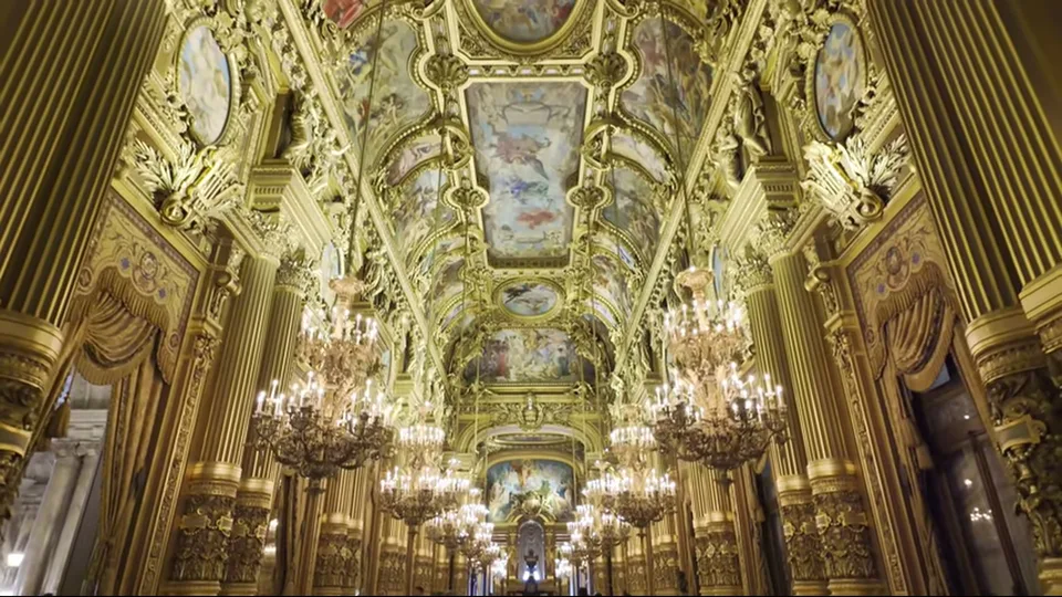 Centered view of Palais Garnier's grand staircase with marble columns and candelabra