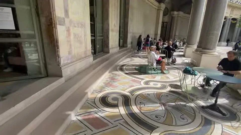 Grand Petit Palais hall with marble walls, mosaic floor, and winged statue
